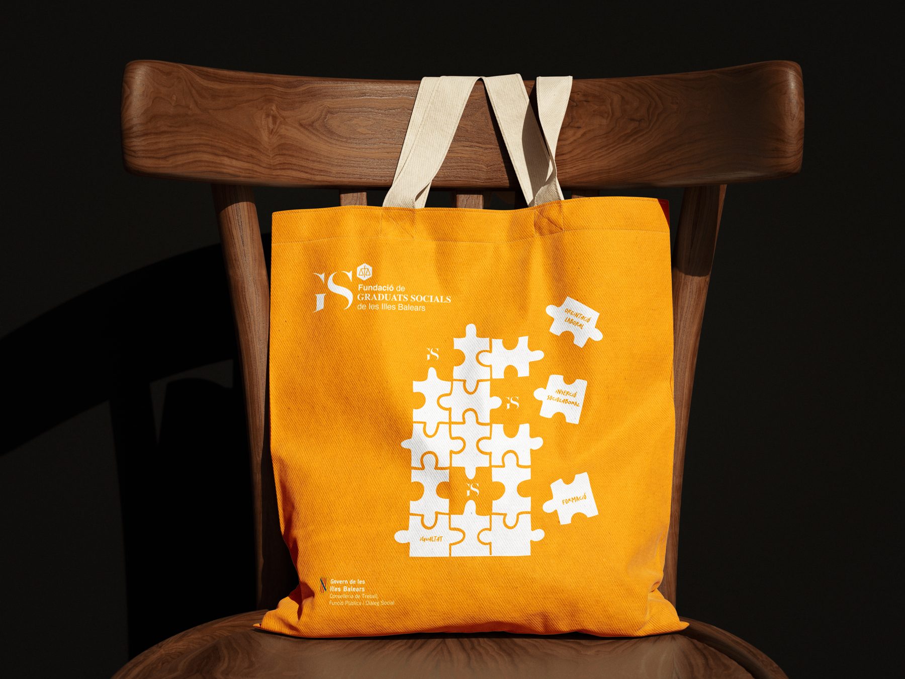 Totebag amarilla de la Fundació de Graduats Socials sobre una silla